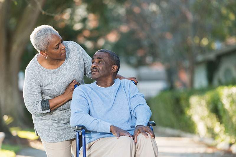woman leaning over man in wheelchair