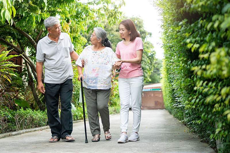 daughter and aging parents link arms to go for a walk