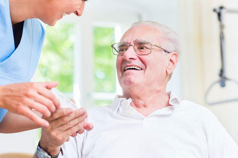 home aid holding an elderly mans hand