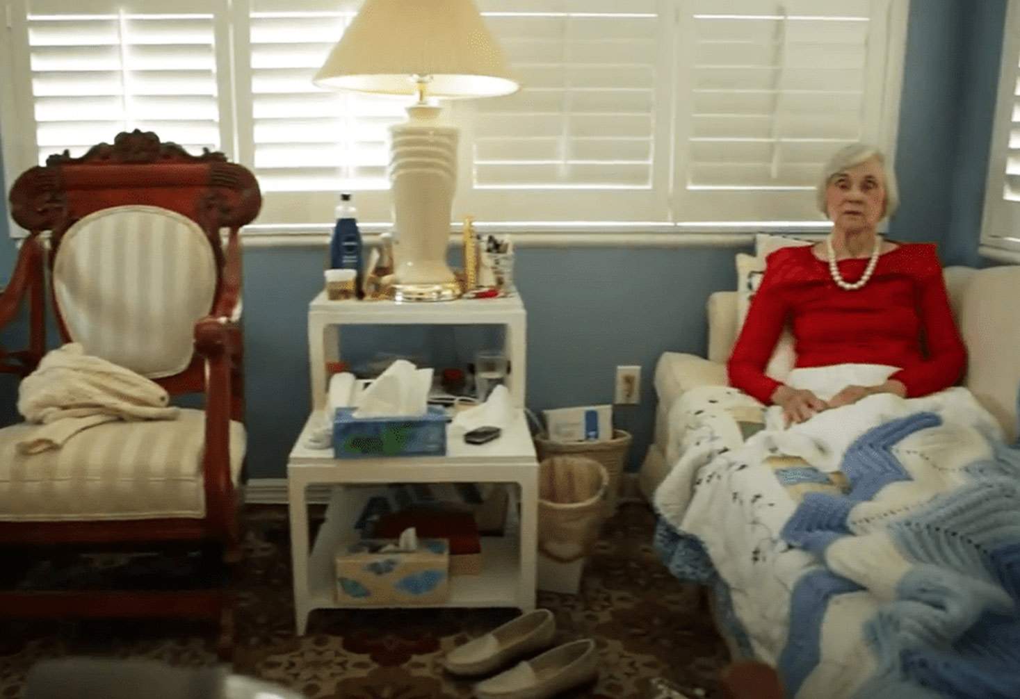 An elderly woman sites in on a couch